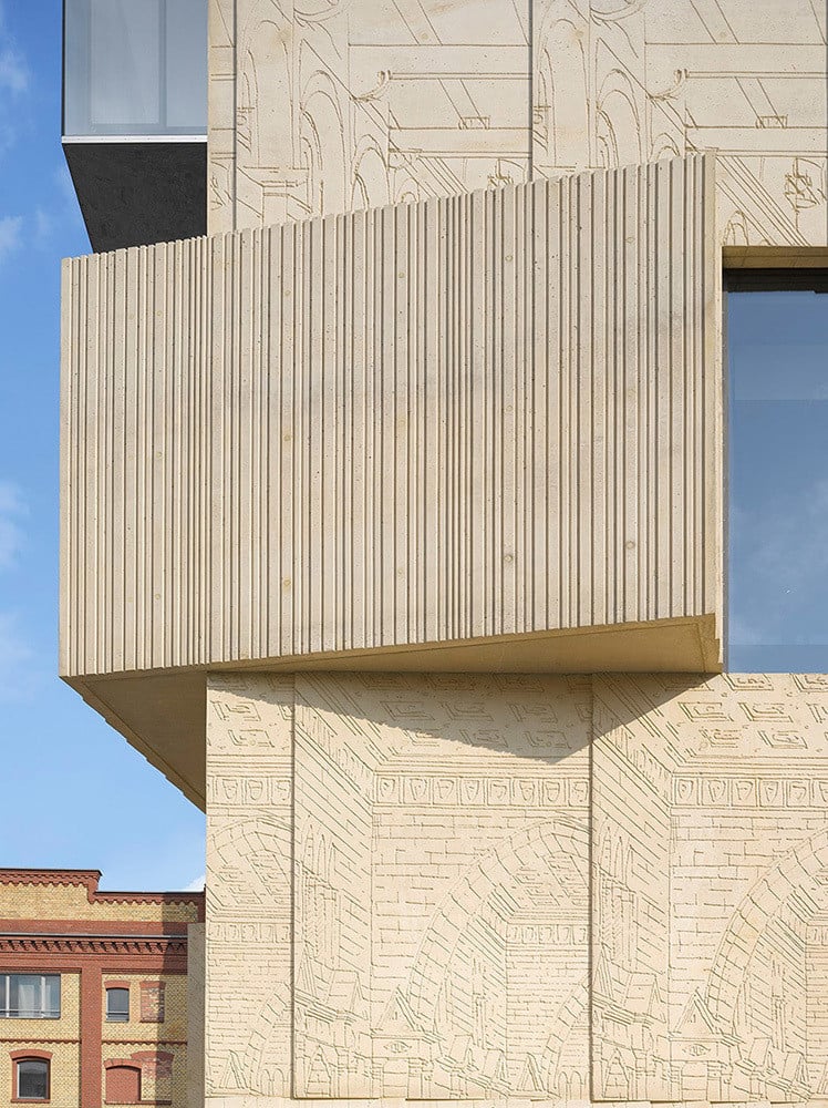 In die Fassade sind Reliefs abstrahierter Architekturzeichnungen eingeprägt