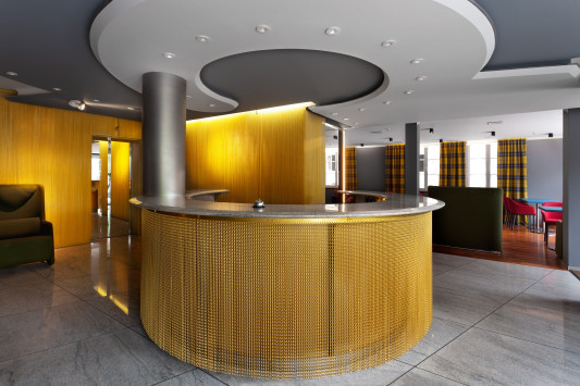 Lobby mit Empfangstresen: goldfarbenes Kettengewebe als Gestaltungselement