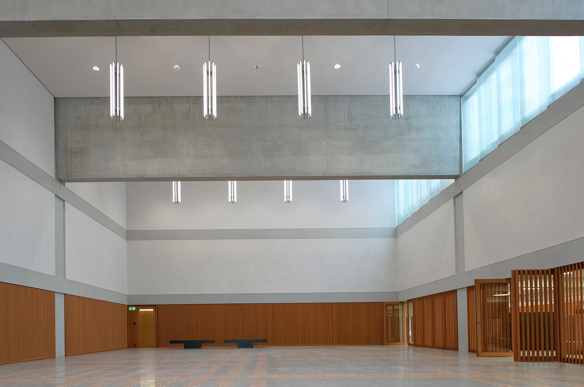 Eingangshalle: Klare Strukturen mit Tragwerk aus Sichtbeton, fein verputzten Wänden, Terrazzo und Holz