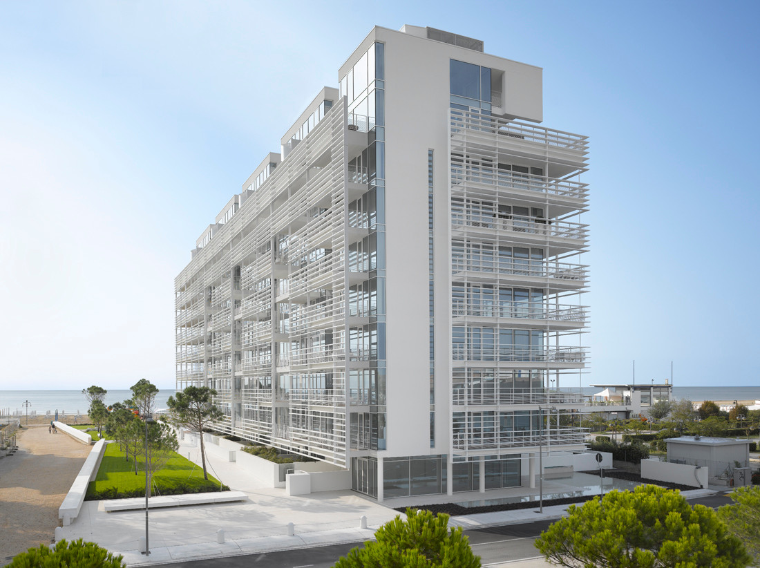 Ein Brise Soleil aus weißen Aluminiumlamellen umschließt das Gebäude zu großen Teilen