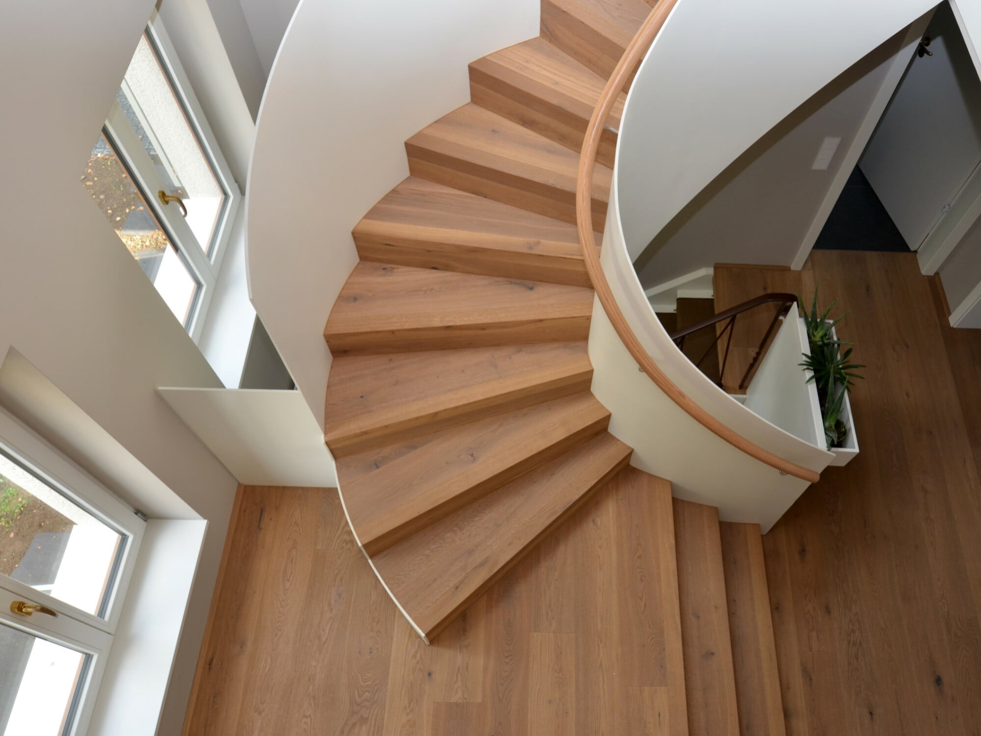 Ellipsoid gerundete Faltwerktreppe aus Stahl mit Holzbelag.