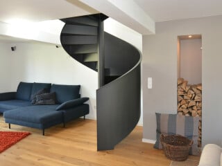 Die Spindeltreppe verläuft schraubenförmig um einen stützenden Mittelpfosten herum, im Bild ein Beispiel mit Brüstungswangen aus Stahlblech