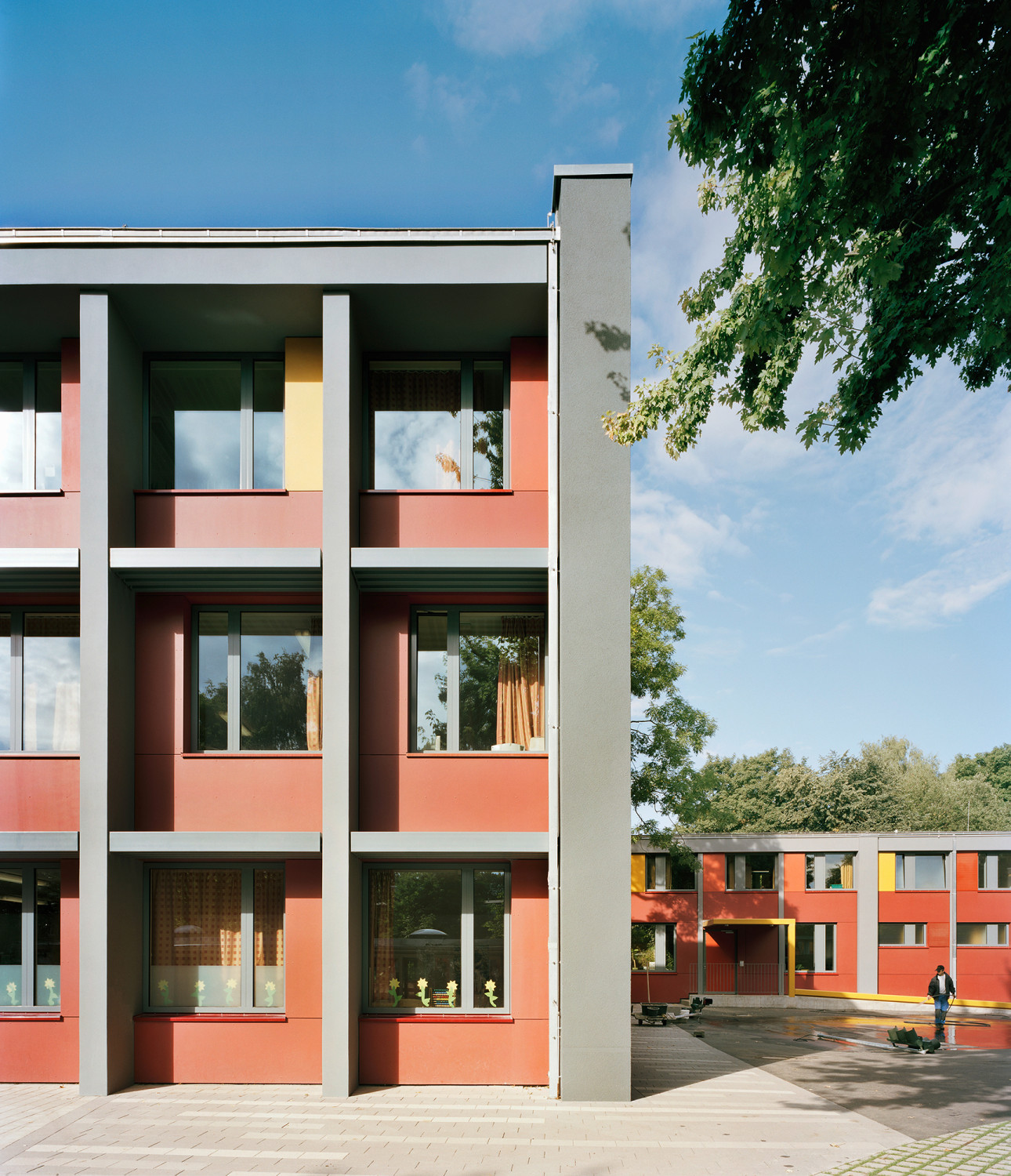 Die Fenster liegen weiter eingerückt in der Fassade als die grau verputzten Elemente - dadurch entsteht ein Relief