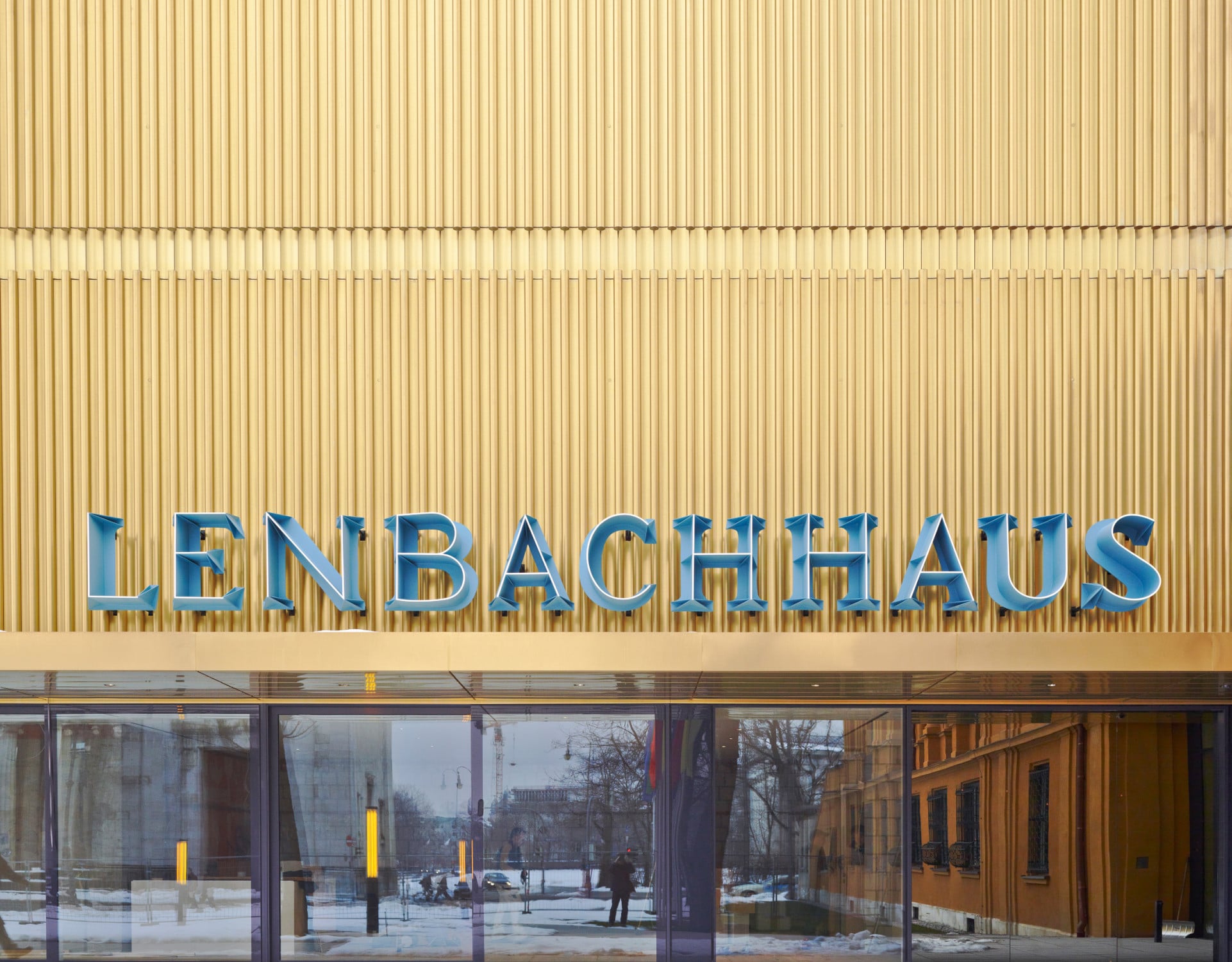 Das Erdgeschoss des Neubaus ist größtenteils verglast, darin spiegelt sich ein Flügel des Altbaus und der Königsplatz