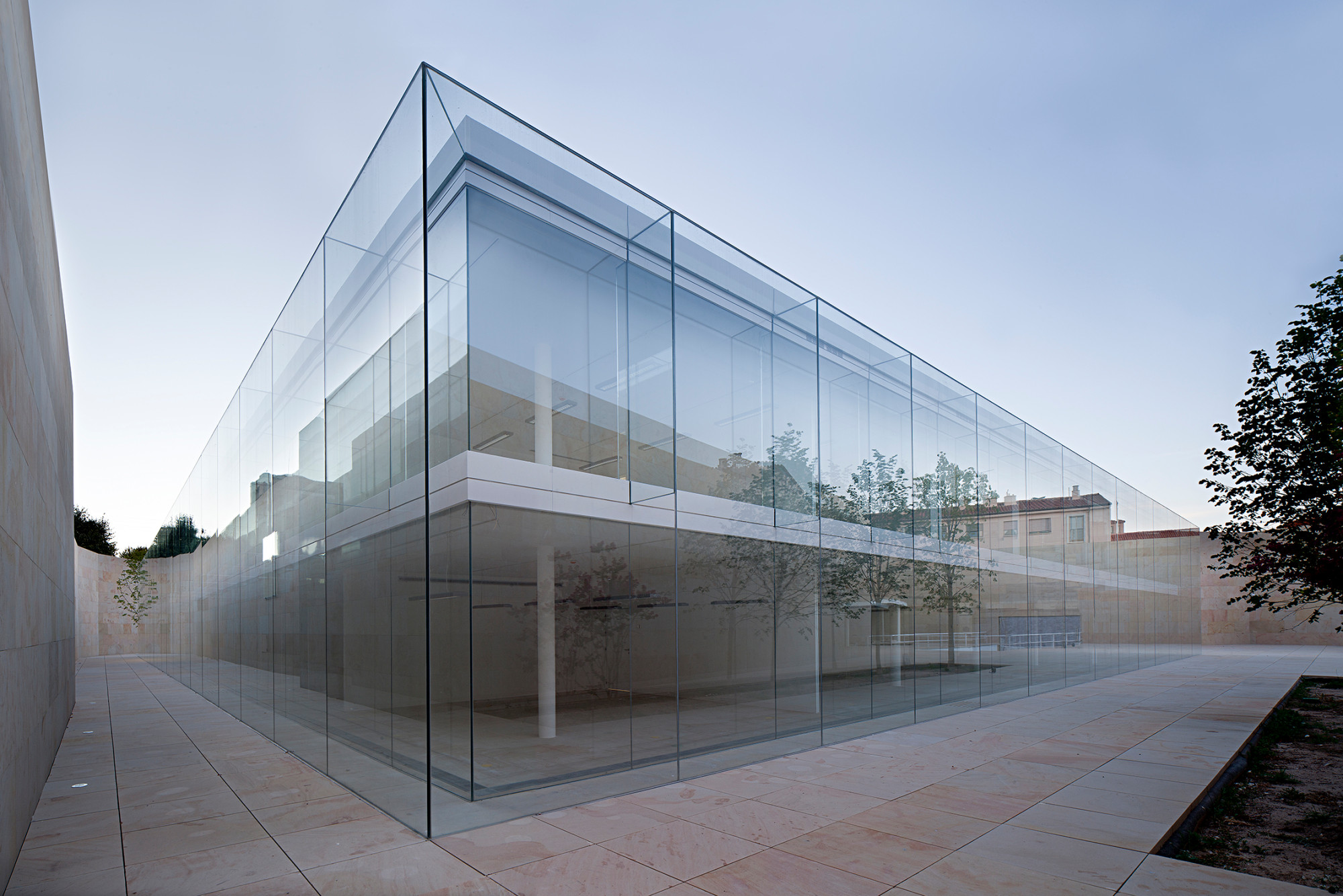 Der zweigeschossige Glasbau ist von einer schützenden Steinmauer umhüllt