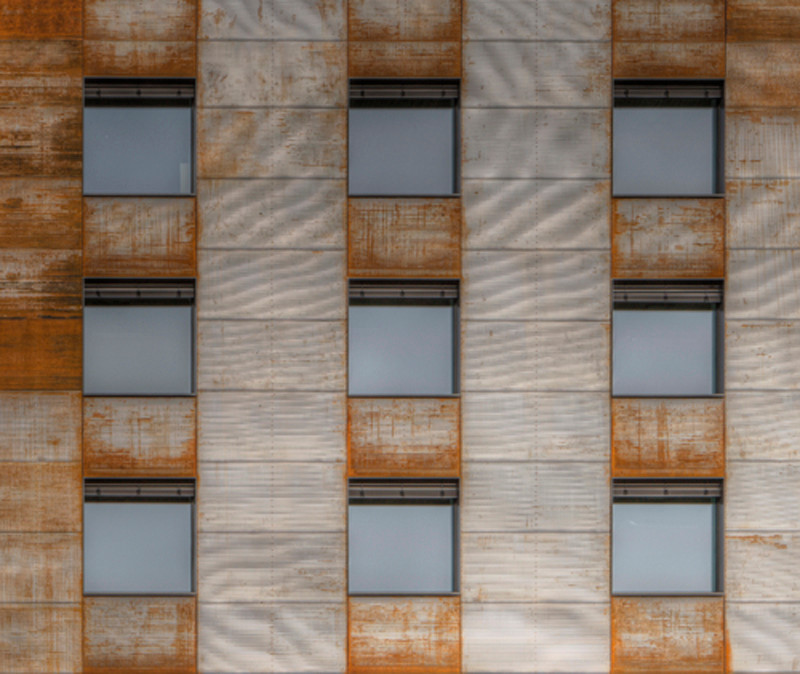 Nach der Sanierung bedecken gewellte Cortenstahlelemente die alte Betonfassade
