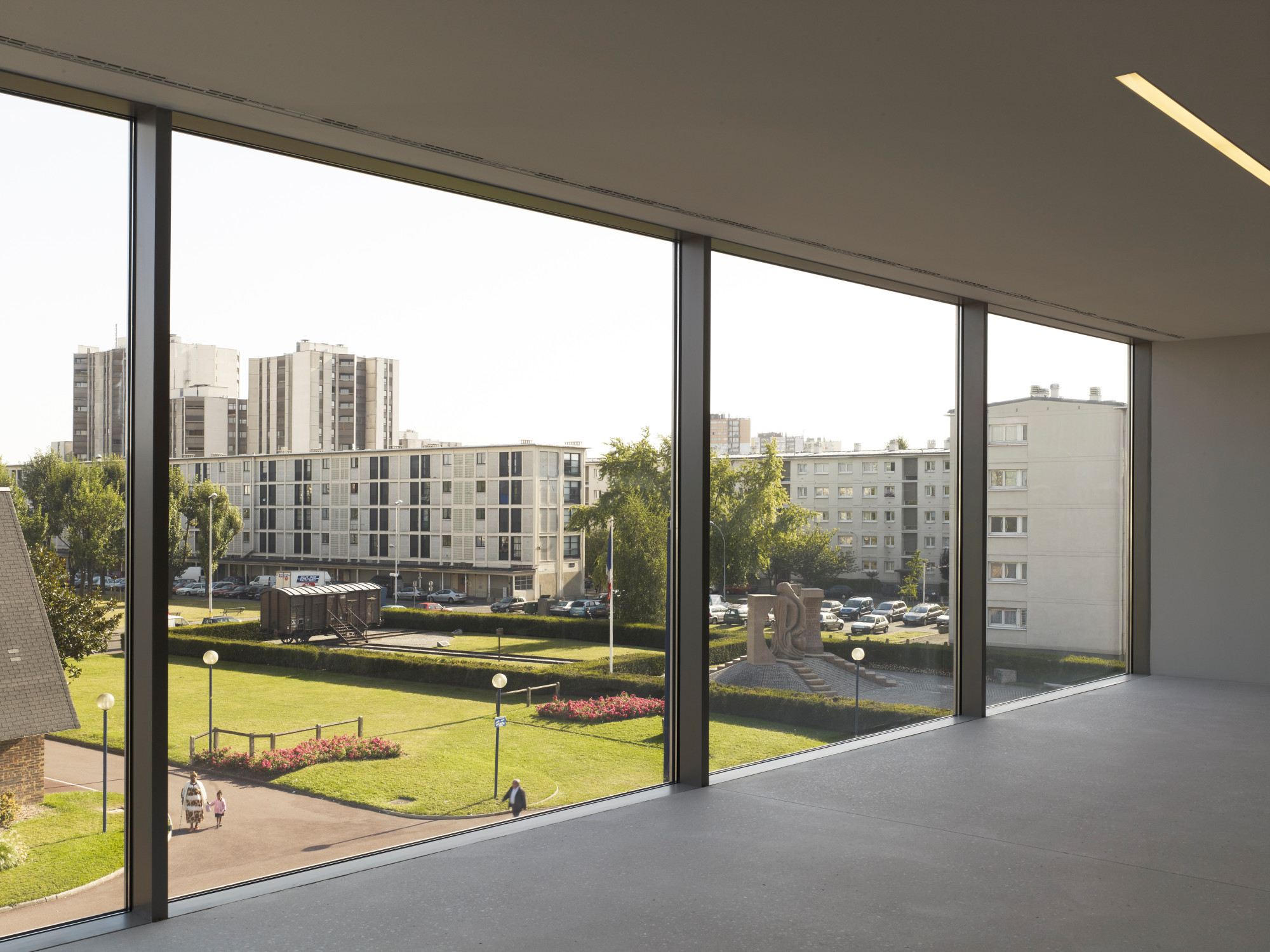 Die Glasfronten lenken den Blick auf das ehemalige Lager mit dem Gebäudekomplex der bis heute bewohnten Cité de la Muette