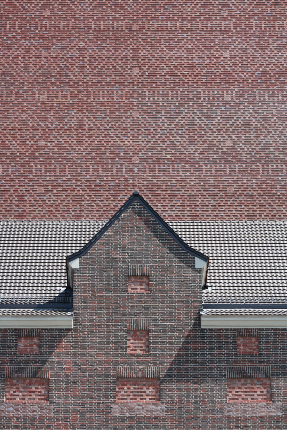 Fassadenausschnitt: Im Vordergrund das alte Speichergebäude mit ausgemauerten Fenstern, im Hintergrund der neue Turm