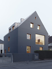 Der Materialmix aus dunkelgrauem Polyethylengewebe, Faserzement und Zinkblech sowie die in der Fassadenebene liegenden Fenster haben den 50er-Jahre-Bau in ein schmuckes Wohnhaus verwandelt