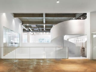 Die weißen Einbauten bilden einen strahlend-hellen Kontrast zum Bestand: links der Konferenzsaal, mittig der Luftraum mit Spindeltreppe, rechts die Räume der Geschäftsleitung