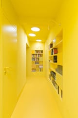 Beim Betreten des Dachgeschosses öffnet sich ein durchgehend in leuchtendem Gelb gestalteter Flur, der als Bibliothek genutzt wird