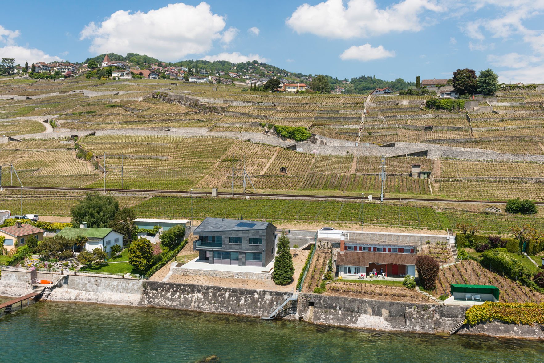 Das Wohnhaus steht auf einem schmalen Uferstreifen am Fuße des Weinbergs von Lavaux