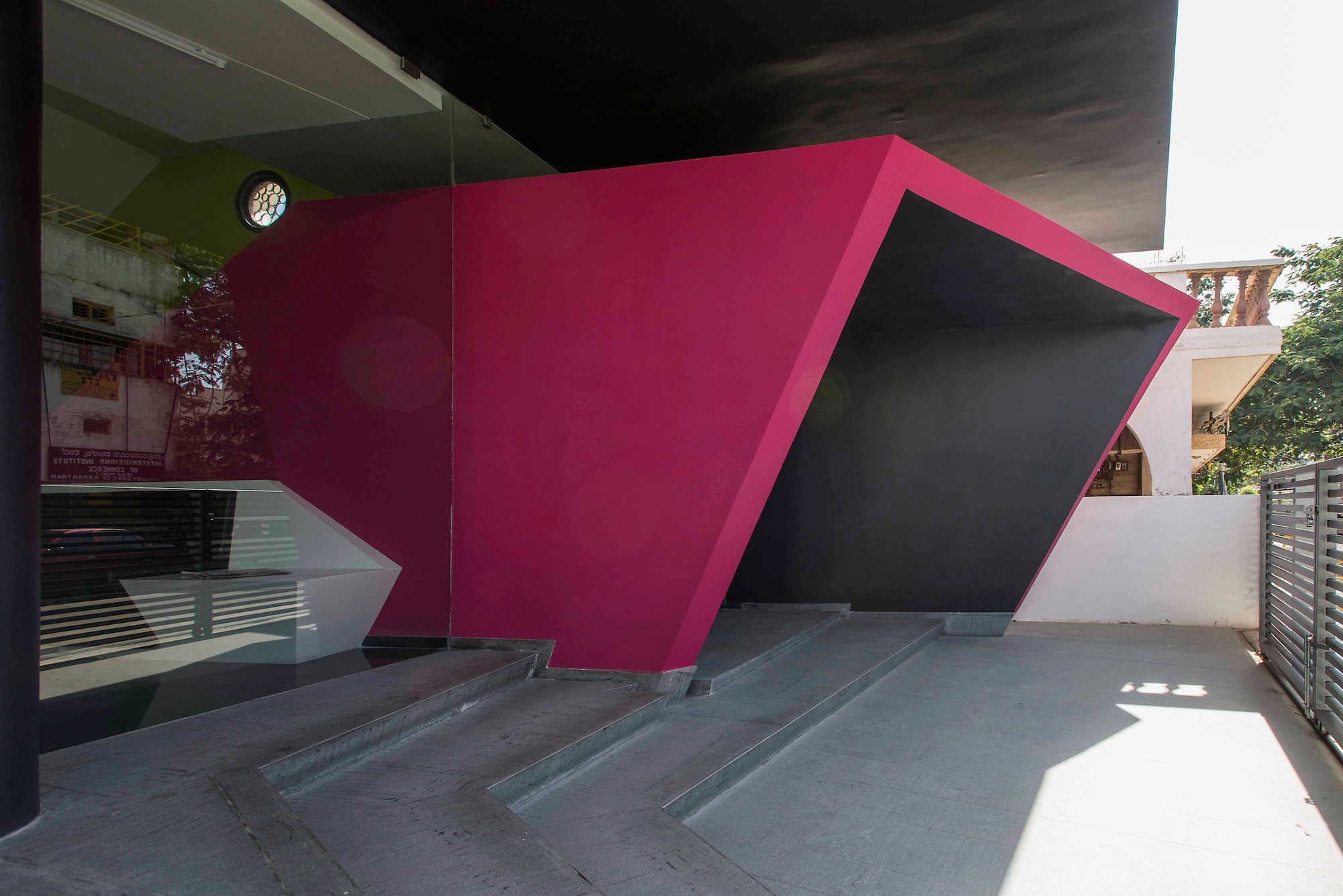 Ein pink-schwarzer, asymmetrisch gefasster Eingang markiert den Übergang zwischen der Außenwelt und der Spiel- und Lernlandschaft