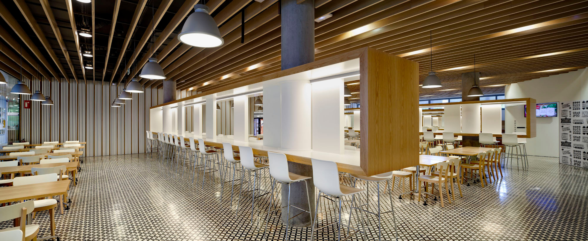 In dem großen Sockel sind viele öffentliche Bereiche untergebracht, wie auch die Cafeteria - ihr Boden wird von weißen Zementfliesen bedeckt, die mit einem Muster aus Zirkelblumen versehen sind