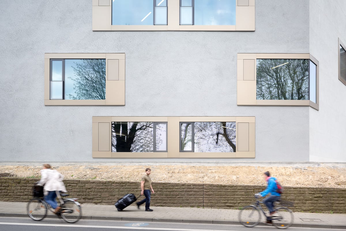 Das Wärmedämmverbundsystem wurde hellgrau verputzt, die der Straße zugewandten Fenster sitzen bündig in der Fassade