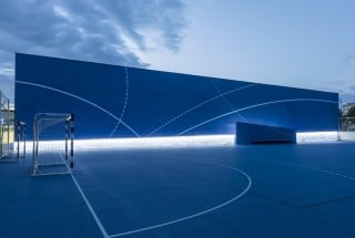 Der blaue Sportboden mit den farbigen Spielfeldmarkierungen wird zum Gestaltungsthema der Fassade