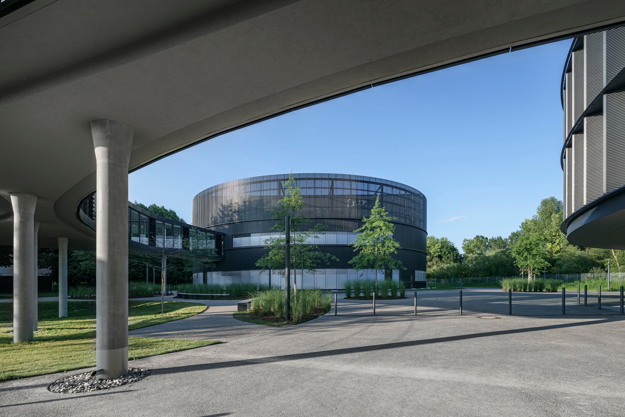 Während das Büro- und Konferenzgebäude großflächig verglast ist, besitzt das Technikgebäude (hier mittig im Bild) nur wenige Fenster und ist mit einer umlaufenden, anthrazitfarbenen Metallfassade verkleidet