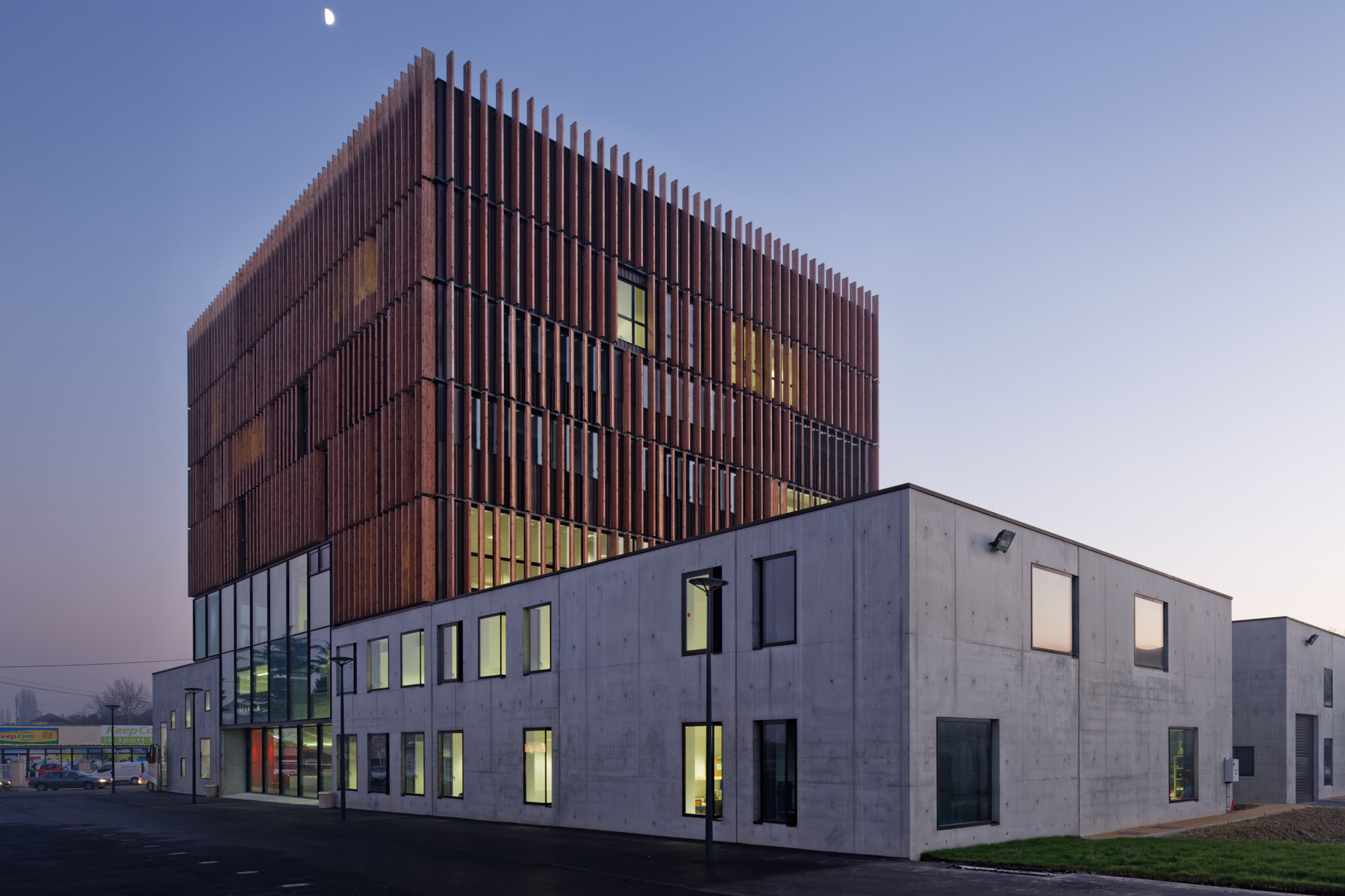 Der zweigeschossige Sockel ist aus Dämmbeton errichtet, der aufgesetzte Baukörper mit Holzlamellen verkleidet 