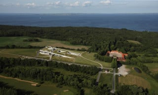 Als eine von Gras, Moos und Blumen bewachsene Dachschräge erhebt sich das Museum aus der hügeligen Landschaft von Skåde