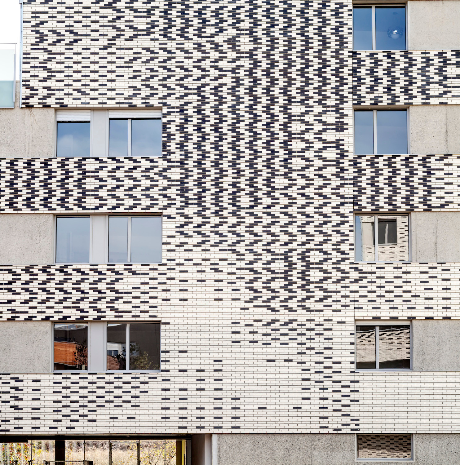 Durch die Überlagerungen von Beton und Mauerwerk werden die Tiefe und Schichtung der Fassade sichtbar