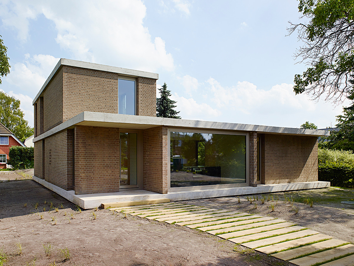 Entwurfsbestimmende Elemente des Wohnhauses sind das Sichtmauerwerk im Wechsel mit großflächigen Verglasungen, Dachränder und Bodenplatte aus Sichtbeton