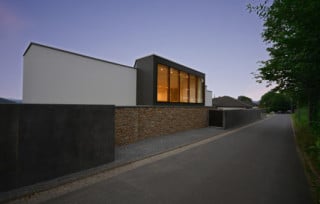 Kontraste in der zur Straße zeigenden Südfassade aus hellem und dunklem Sichtbeton und Bruchsteinmauerwerk