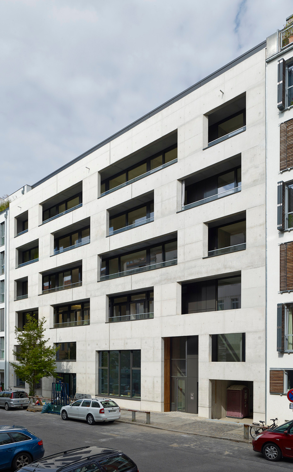 Während den Obergeschossen eine Loggienebene vorgelagert ist, liegen die Fenster des öffentlich nutzbaren Erdgeschosses in der vorderen Fassadenebene
