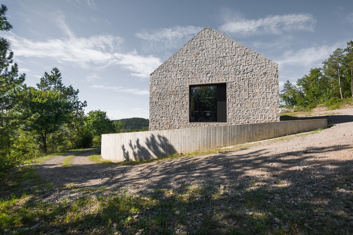Die Außenwände aus grob behauenen Kalksteinen mit Betonverfüllung gehen nahtlos in das geneigte Satteldach über und lassen das Haus wie aus einem Guss erscheinen