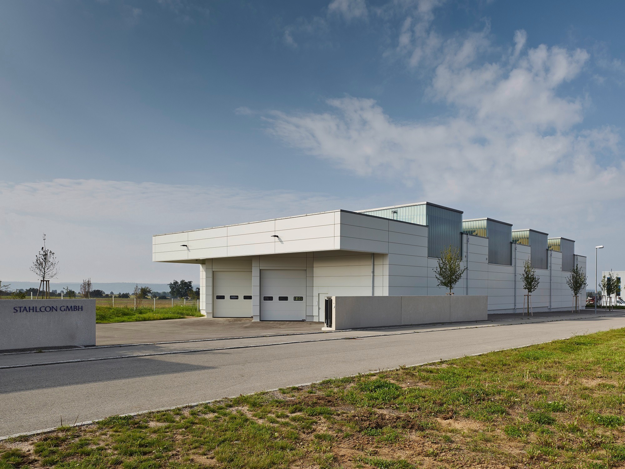 Ansicht Nordost: Die Zufahrt zur Lagerhalle erfolgt über einen Vorplatz und zwei große Tore in der gefalteten Fassade