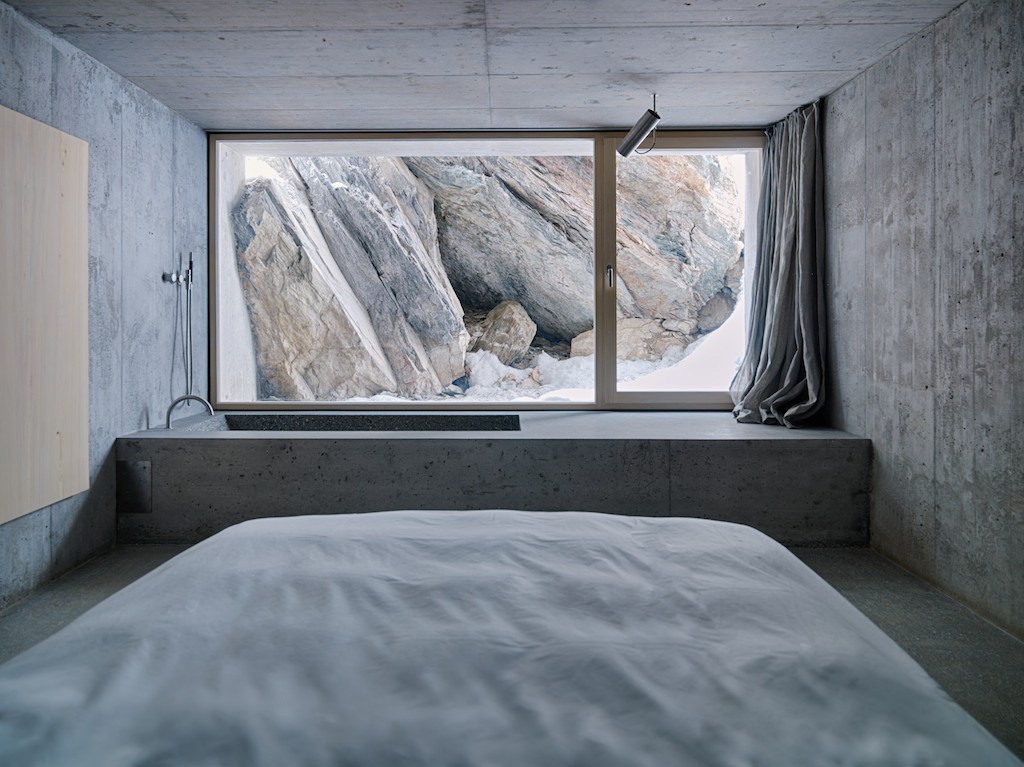 Schlafraum mit Badewanne und Ausblick zur Felswand im Untergeschoss