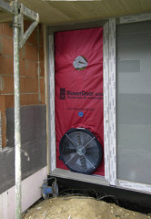 Um undichte Stellen in der Gebäudehülle aufzuspüren, wird in eine Außentür ein abgedichteter Rahmen mit einem Ventilator eingebaut, der einen Unterdruck im Gebäude erzeugt