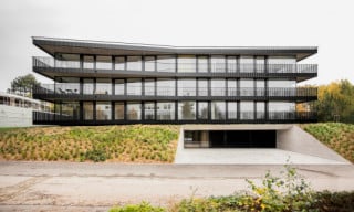 Umlaufend auskragende Balkone, kontrastreiche Materialien, Rundumverglasungen und feinsinnig verzerrte Geometrien verleihen dem dreigeschossige Wohnhaus eine beschwingte Wirkung