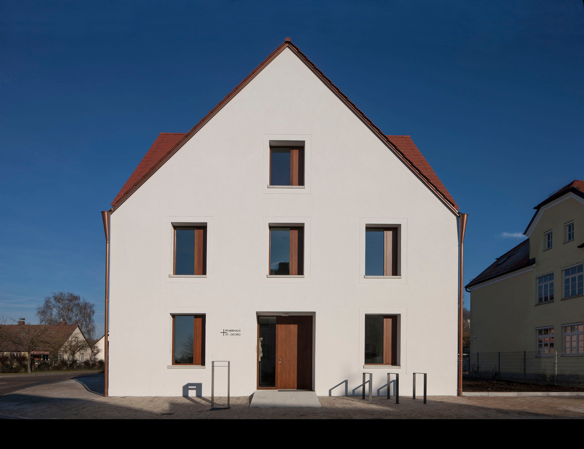 Die Spiegelsymmetrie, die im Baukörper angelegt ist, wird durch die Anordnung von jeweils drei Fensterachsen in jeder Fassade unterstützt