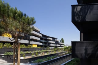 Blick von Süden in den Hof des Wohnblocks: links ist die Ostfassade des längeren Baukörpers zu sehen, im Anschnitt rechts die Balkone des kürzeren, geraden Baukörpers