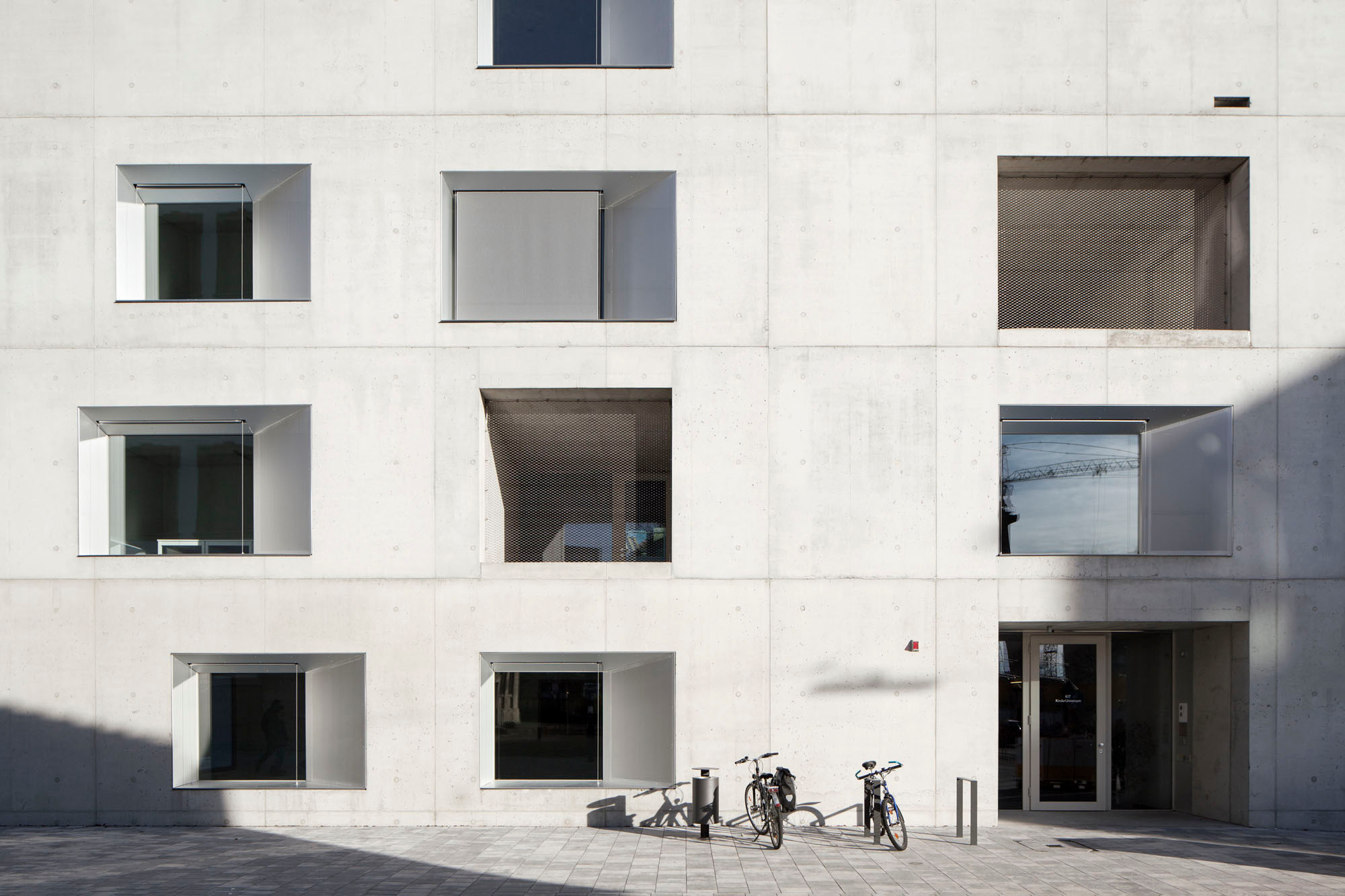 Die Einfassungen der Fenster und die feinen Gitternetze vor den Loggien bilden einen feinen Kontrast zur Fassade aus Sichtbeton