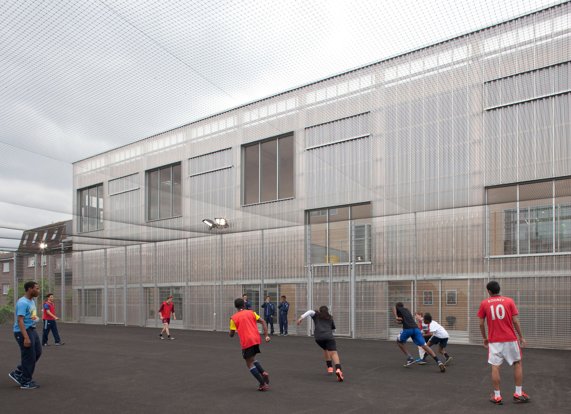 Vor der Ostfassade liegt der Sportplatz, ein Wintergarten dient als thermische und akustische Pufferzone