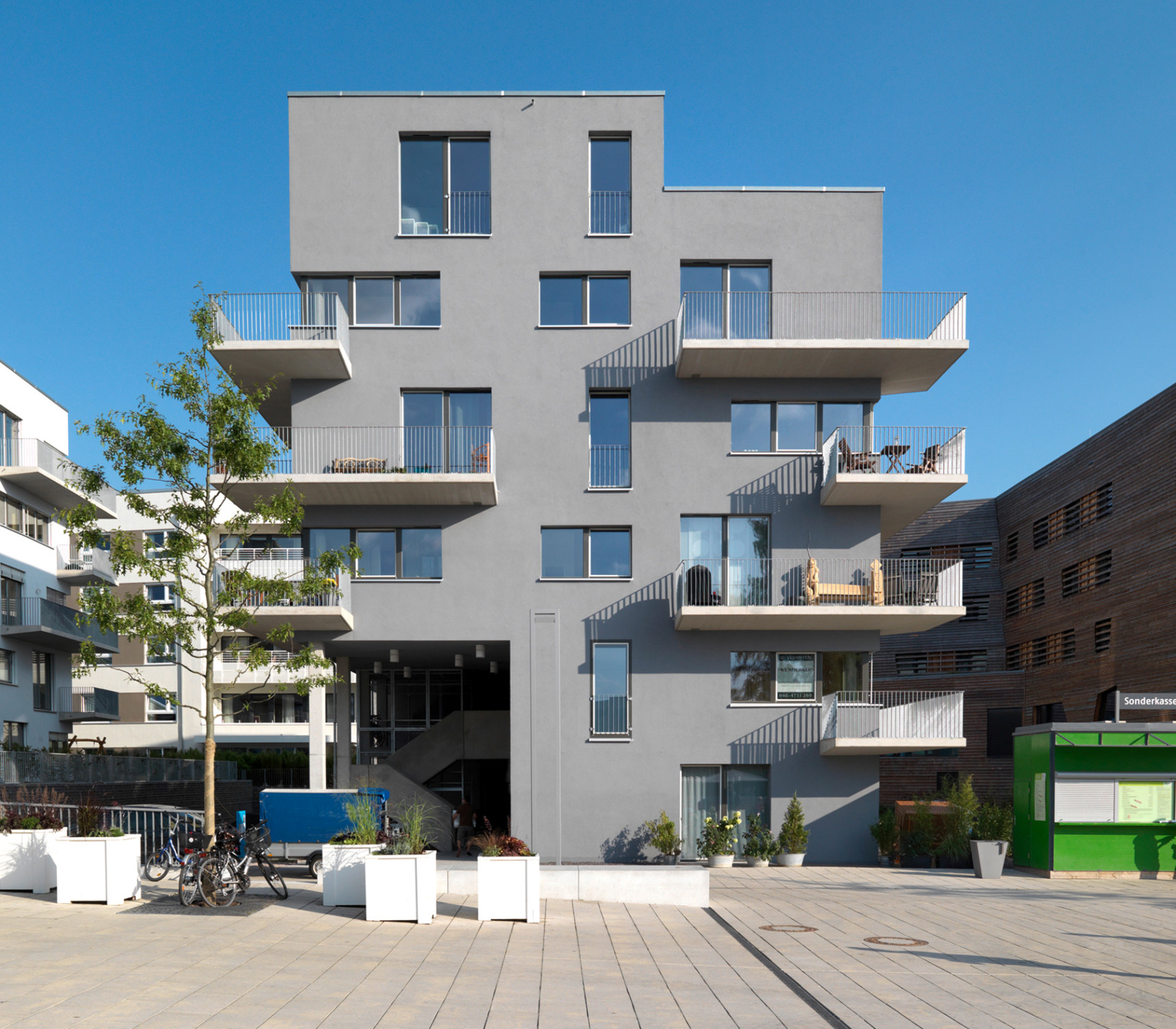 Unregelmäßig angeordnete, teils liegende, teils stehende und auch um die Gebäudeecken greifende Fensteröffnungen und unterschiedlich über Eck auskragende Balkone sorgen für ein lebhaftes Fassadenbild