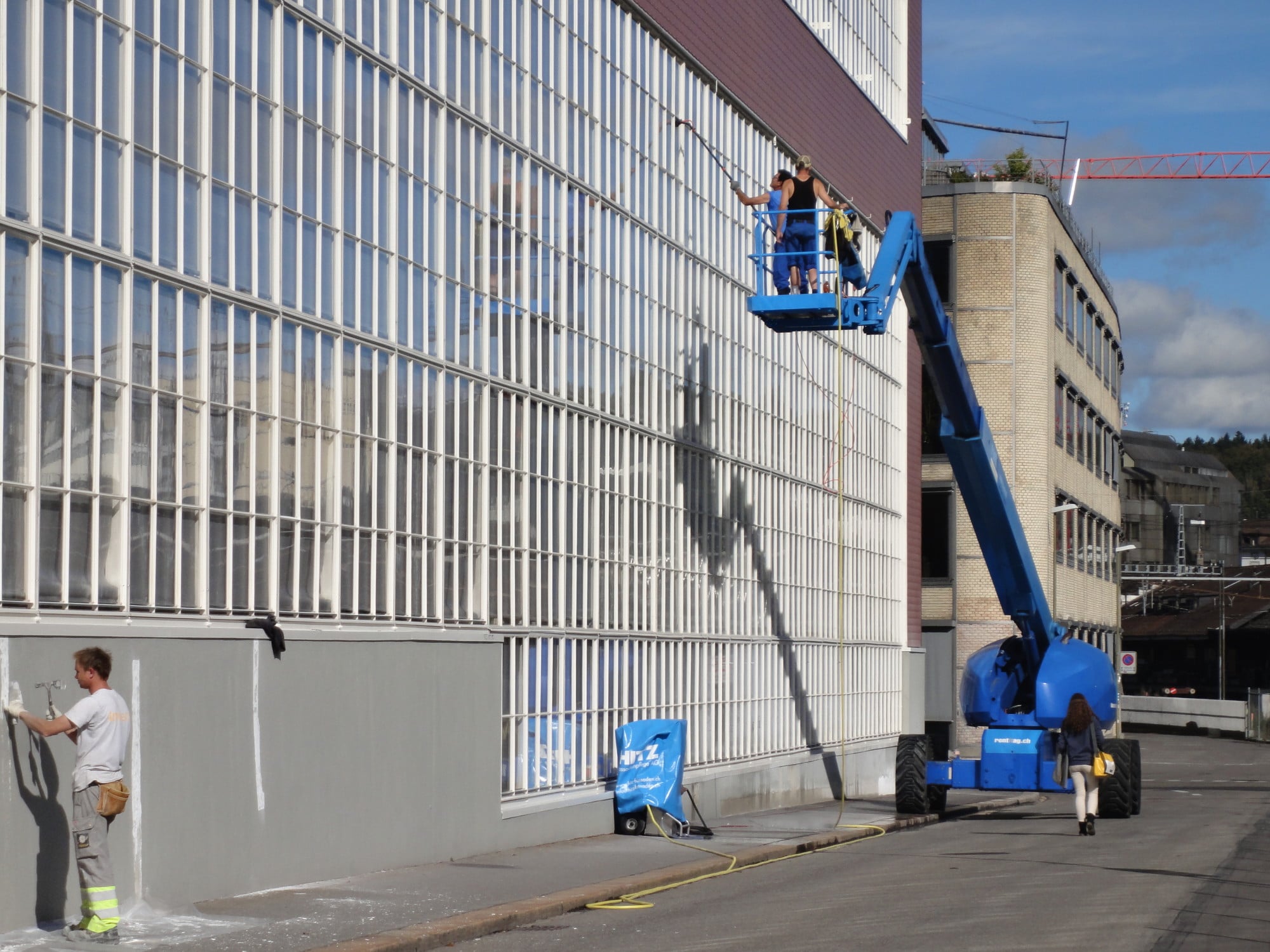 Charakteristisch für das gesamte Bauwerk ist seine Vorhangfassade mit großflächigen, membranartigen Glasflächen und einer Bekleidung mit roten Faserzementschindeln
