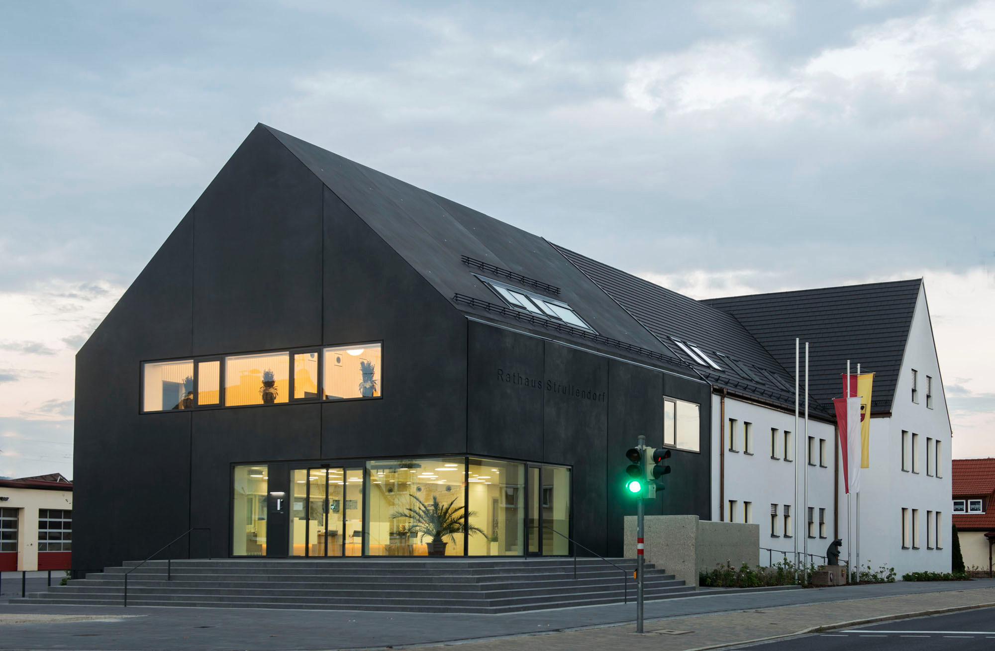 Gleiche Bauflucht, gleiche Höhe und gleiche Satteldachform - und  dennoch ist die Rathauserweiterung ein deutlich andersartiges Haus