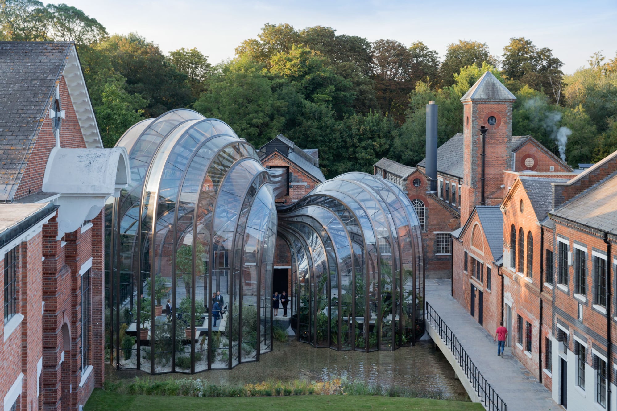 Wie Wasserfontänen scheinen sich die Glashäuser aus dem Backsteinbau in den Fluss zu ergießen