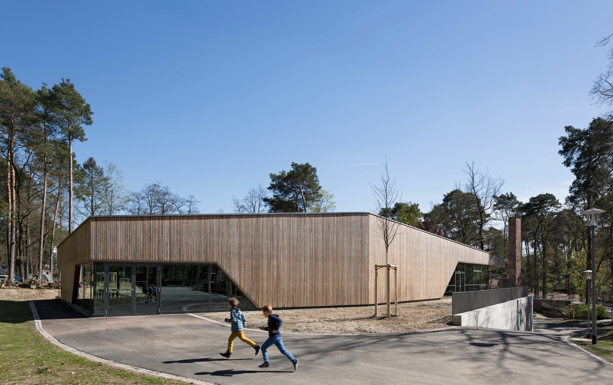 Die kantige Kubatur, die vertikale Schalung aus Lärchenholz, Glaseinschnitte und Sichtbeton prägen den neuen Sport- und Mehrzweckbau (Nordwestansicht)
