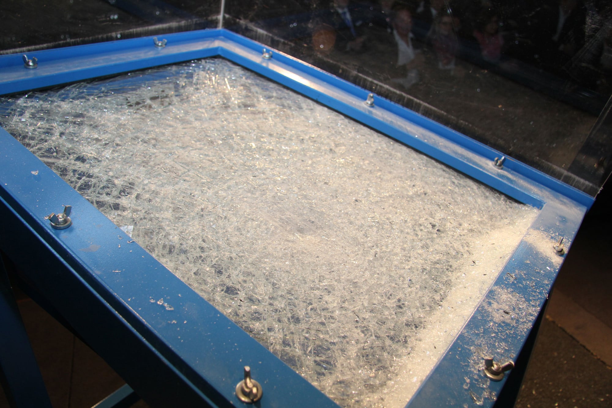Während die äußere Glasscheibe in stumpfkantige Splitter zerbricht, bleibt die innere Polycarbonatscheibe intakt