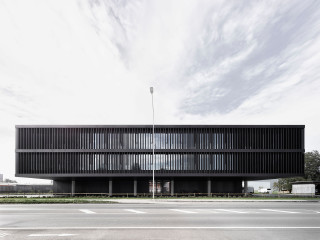 Die zwei Bürogeschosse der Firmenzentrale scheinen über der großen Asphaltfläche der Spedition zu schweben