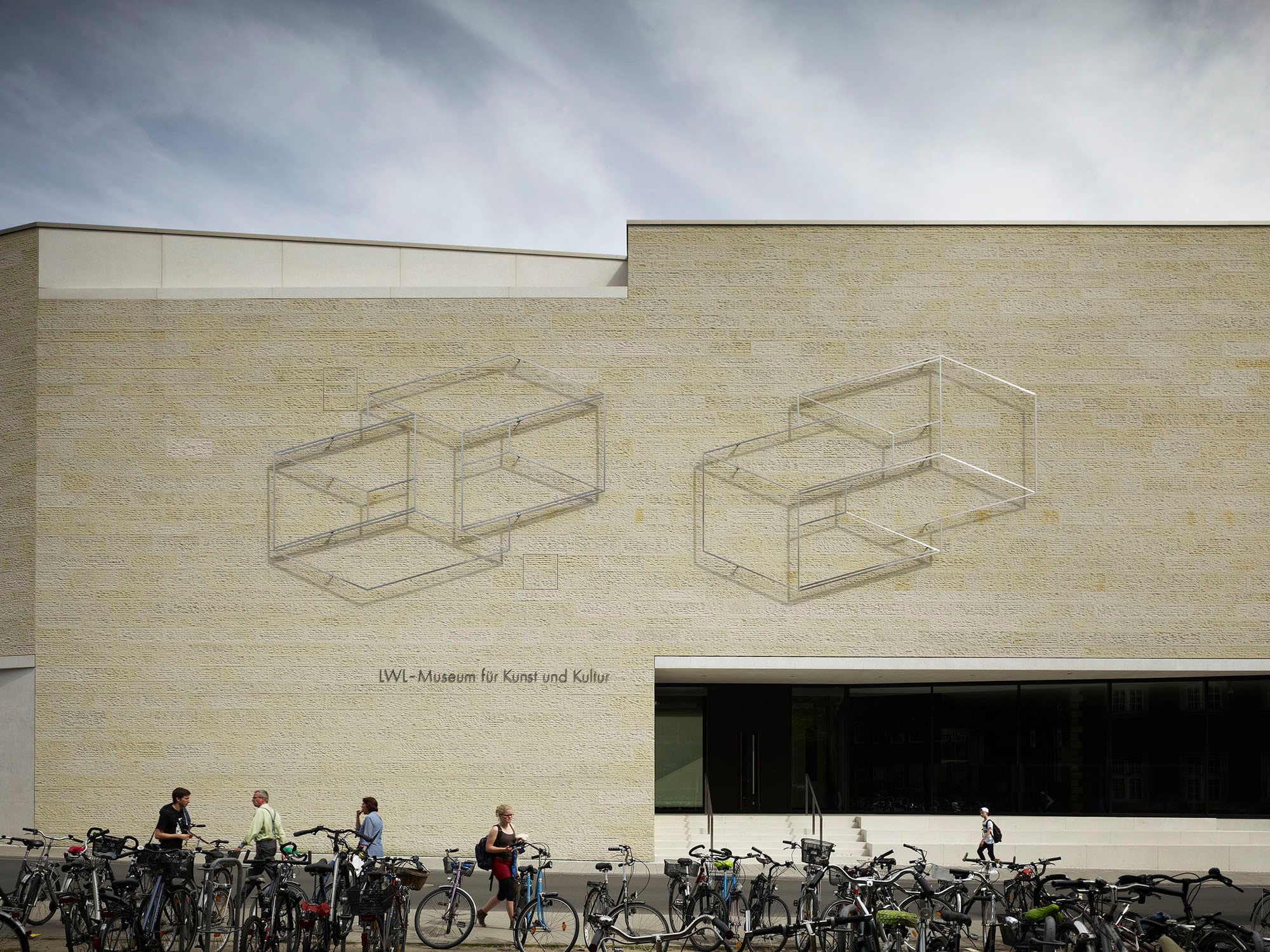 Vor dem hellen Sandstein der Westfassade ist eine filigrane Arbeit von Josef Albers angebracht, die bereits den Vorgängerbau aus den 1970er-Jahren schmückte