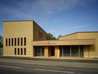 Das Besuchszentrums setzt sich aus drei Baukörpern zusammen: zwei kompakten Lehmbauten mit polygonalem Grundriss und einem verbindenden, großflächig verglasten Mittelteil (Abb. Ostfassade)