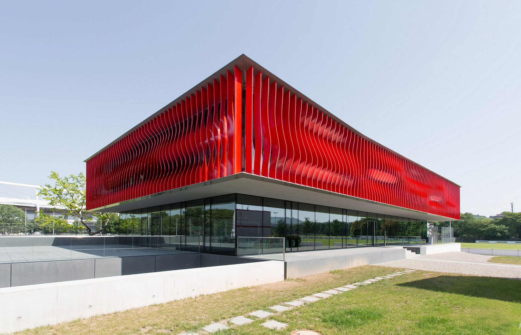 Der Neubau thront auf einem gläsernen Erdgeschoss und einem unterirdischen, lang gestreckten Sockelgeschoss, in das ein eingeschnittener Hof Tageslicht hineinführt (Ansicht Südost)