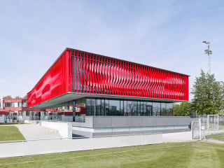 Der zeichenhafte Bau des neuen Jugendleistungszentrum ist im Obergeschoss von leuchtend roten Lamellen umhüllt (Ansicht Nordost)