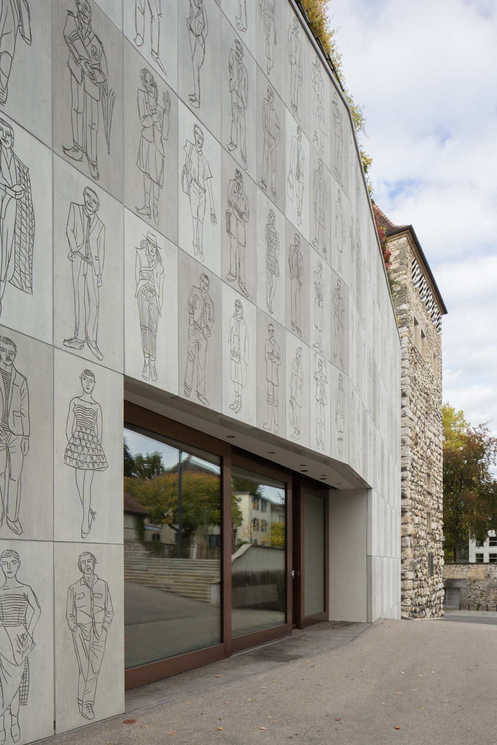 Die Fassade aus 134 vorgehängten Betontafeln mit Skizzen von Menschen ist eine Arbeit des Künstlers Josef Felix Müller