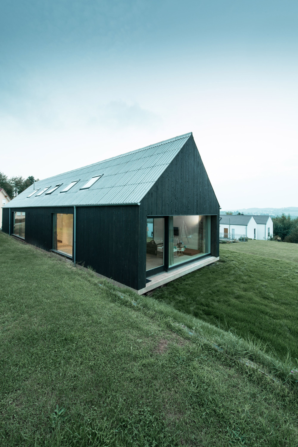 An den beiden Giebelseiten reichen die Räume jeweils bis hinauf zum First: hier das Wohnzimmer, gegenüber der Eingang mit Garage