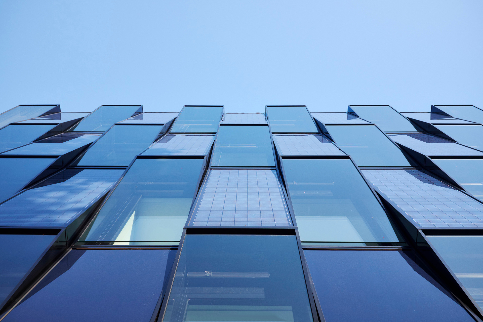 Mit den optischen Effekten seiner glänzenden, teilweise aus Photovoltaikelementen gebildeten Fassade macht das Blauhaus deutlich, dass es auf allen Etagen um Energieeffizienz geht